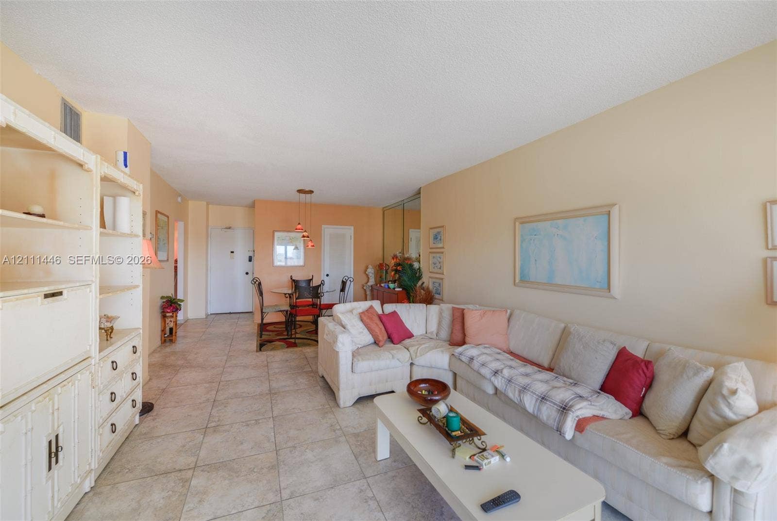 1965 S Ocean Drive, #15M, Hallandale Beach, Hallandale Beach, FL 33009 Open-concept living area featuring large-format ceramic tile flooring, built-in floor-to-ceiling storage cabinetry, mirrored wall panels, and multi-pendant overhead lighting