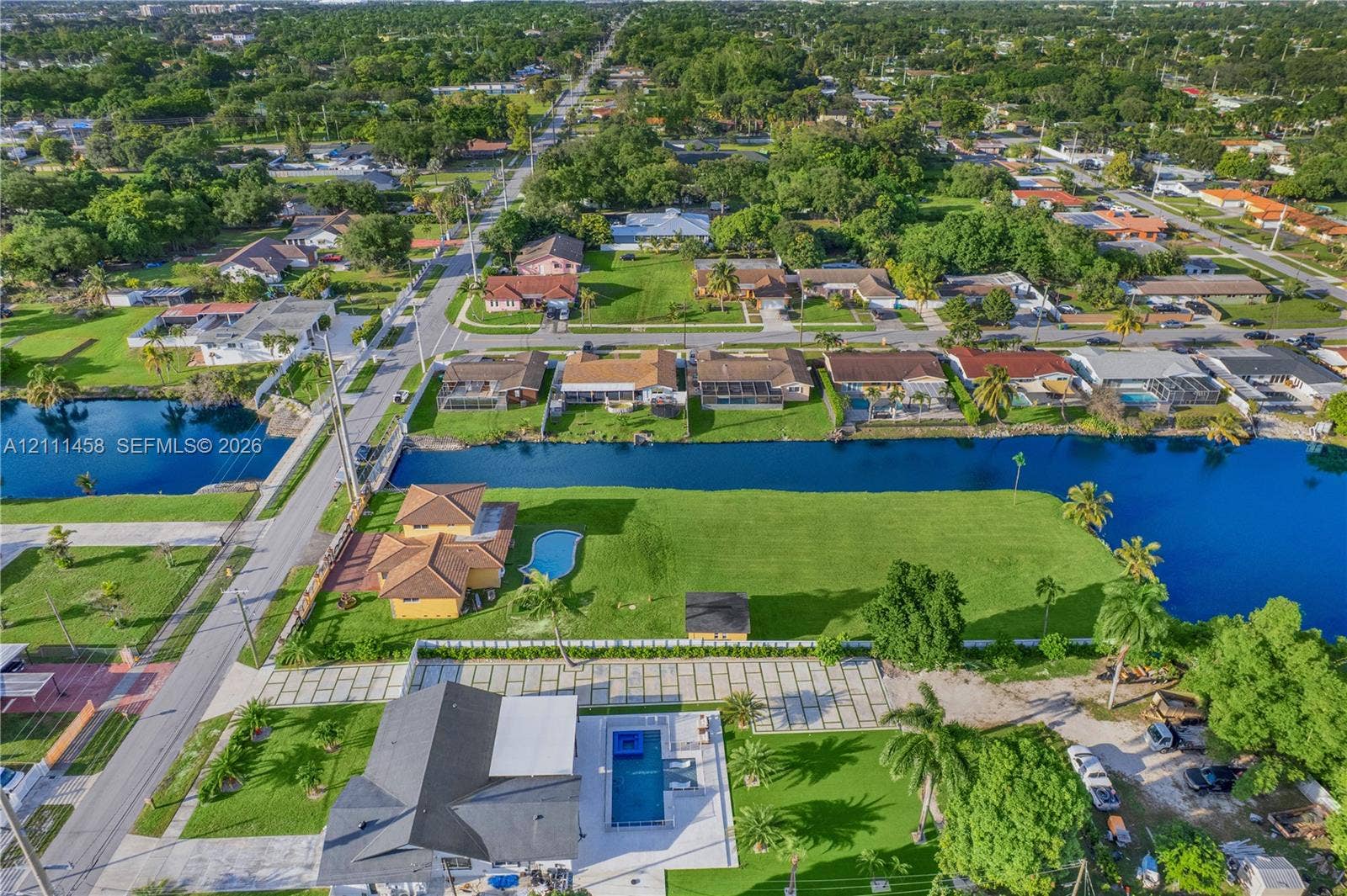 17135 NW 19th Avenue, Miami Gardens, FL 33056 Aerial perspective of a waterfront property featuring a canal-front bulkhead, expansive lawn, swimming pool, and concrete paver driveway
