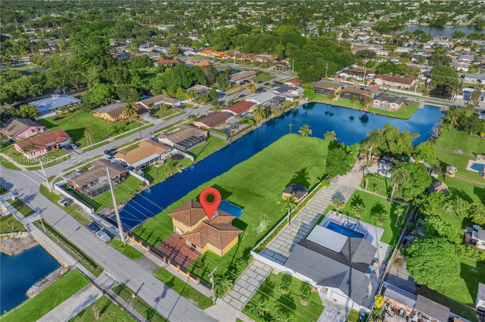 17135 NW 19th Avenue, Miami Gardens, FL 33056 Aerial perspective of a single-family residence featuring a tiled roof, a private swimming pool, and direct canal frontage