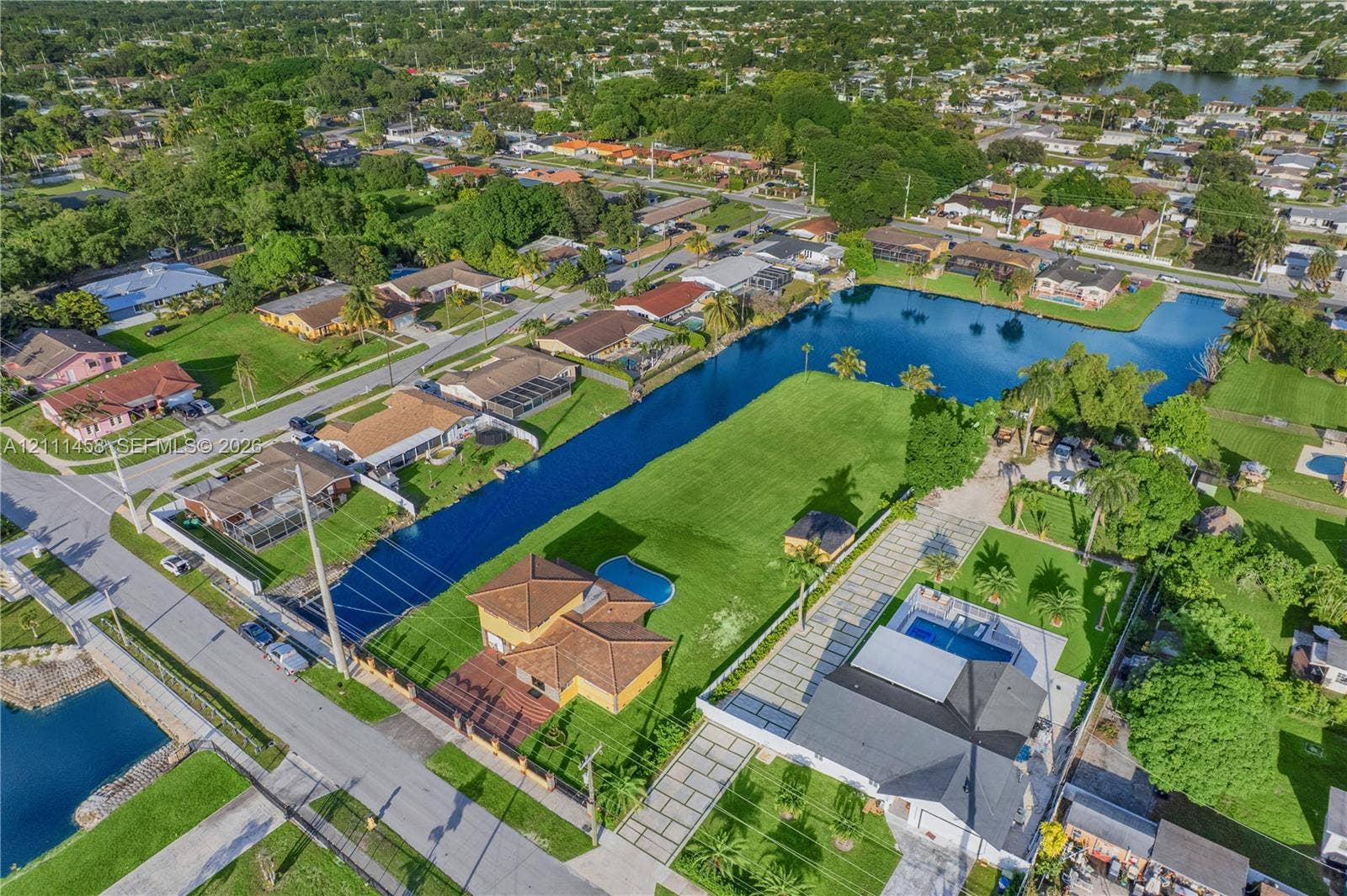 17135 NW 19th Avenue, Miami Gardens, FL 33056 Waterfront lot featuring a sprawling lawn, a private swimming pool, and an expansive paver driveway