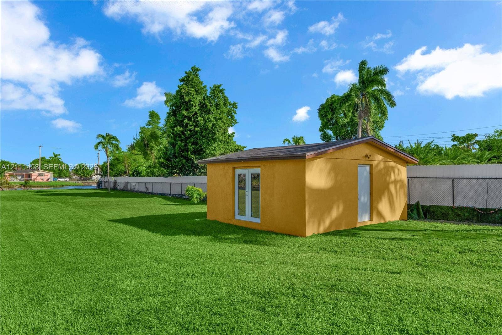 17135 NW 19th Avenue, Miami Gardens, FL 33056 Expansive backyard featuring a manicured lawn, a detached outbuilding, French doors, and perimeter fencing