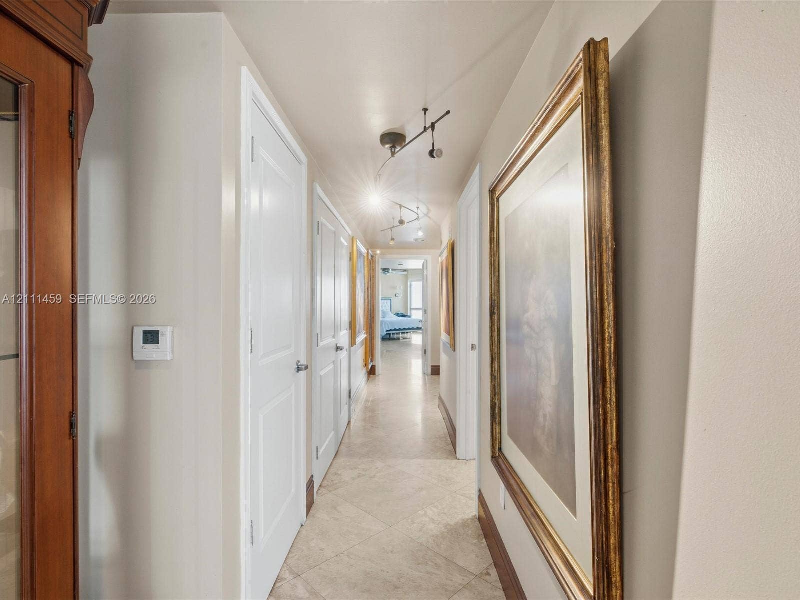 Hallway featuring large-format tile flooring, multi-panel doors, and adjustable track lighting