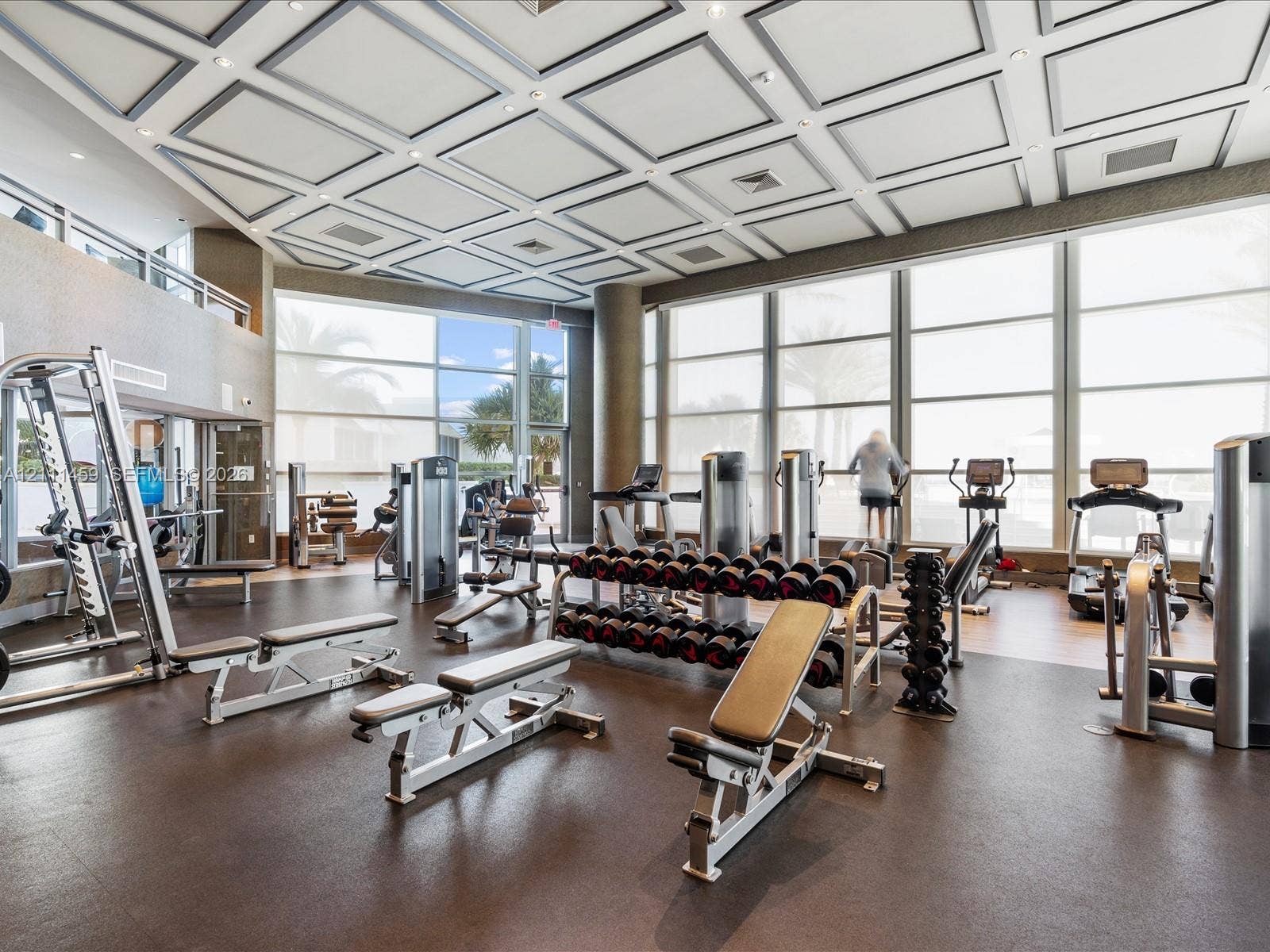 Fitness center featuring a coffered ceiling, floor-to-ceiling windows, and impact-resistant rubber flooring