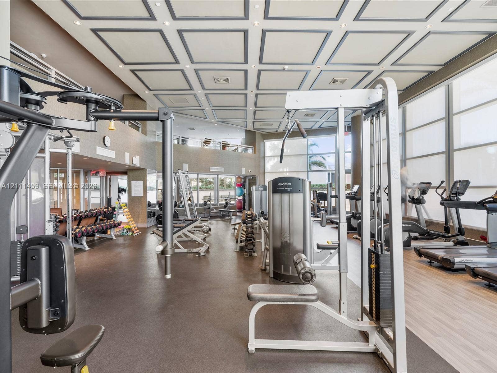 Fitness facility featuring a coffered ceiling, floor-to-ceiling windows, and recessed lighting