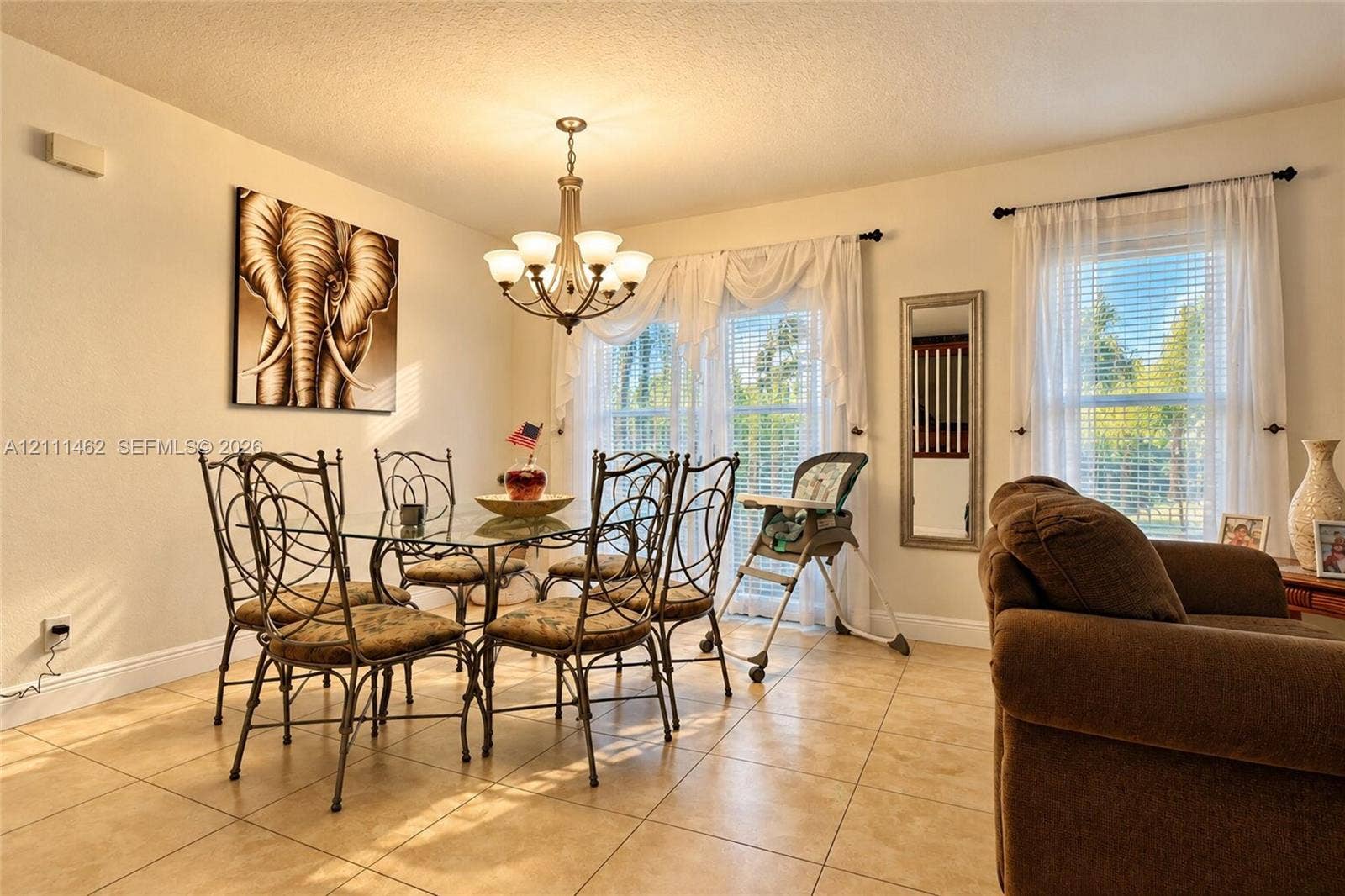 Ceramic tile flooring, classic multi-arm chandelier, and dual windows with horizontal blinds