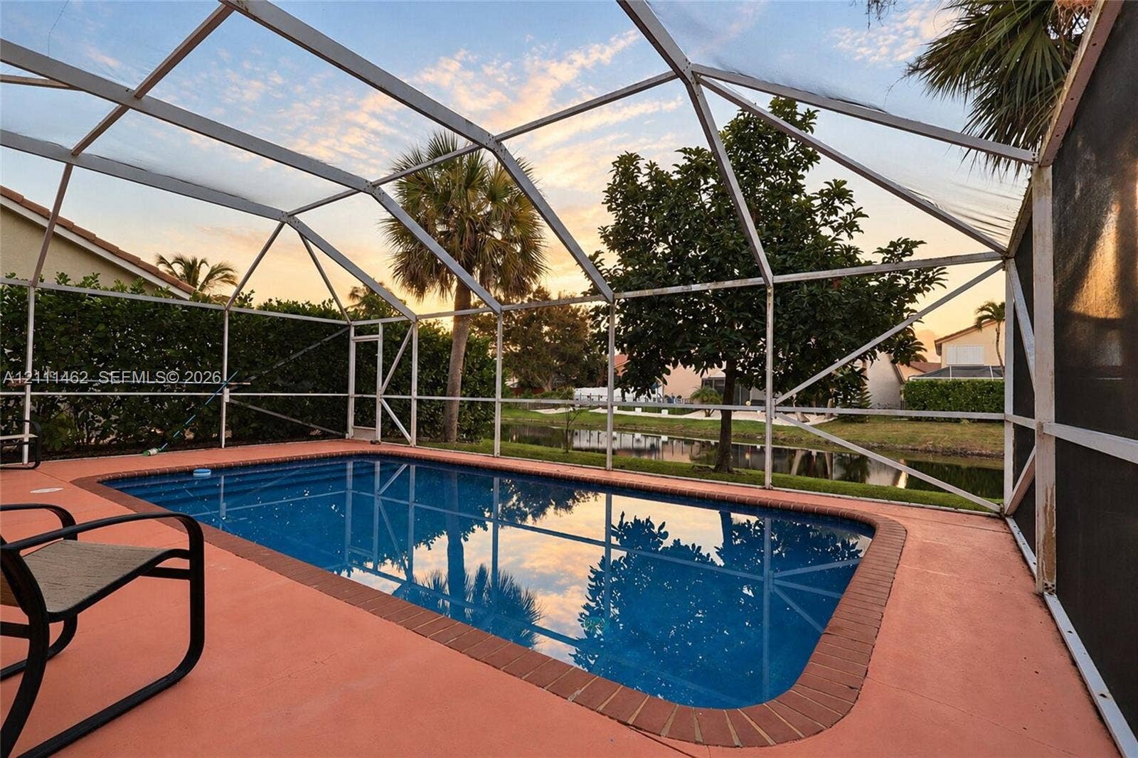 Screened-in pool enclosure with a brick-paver border and concrete deck
