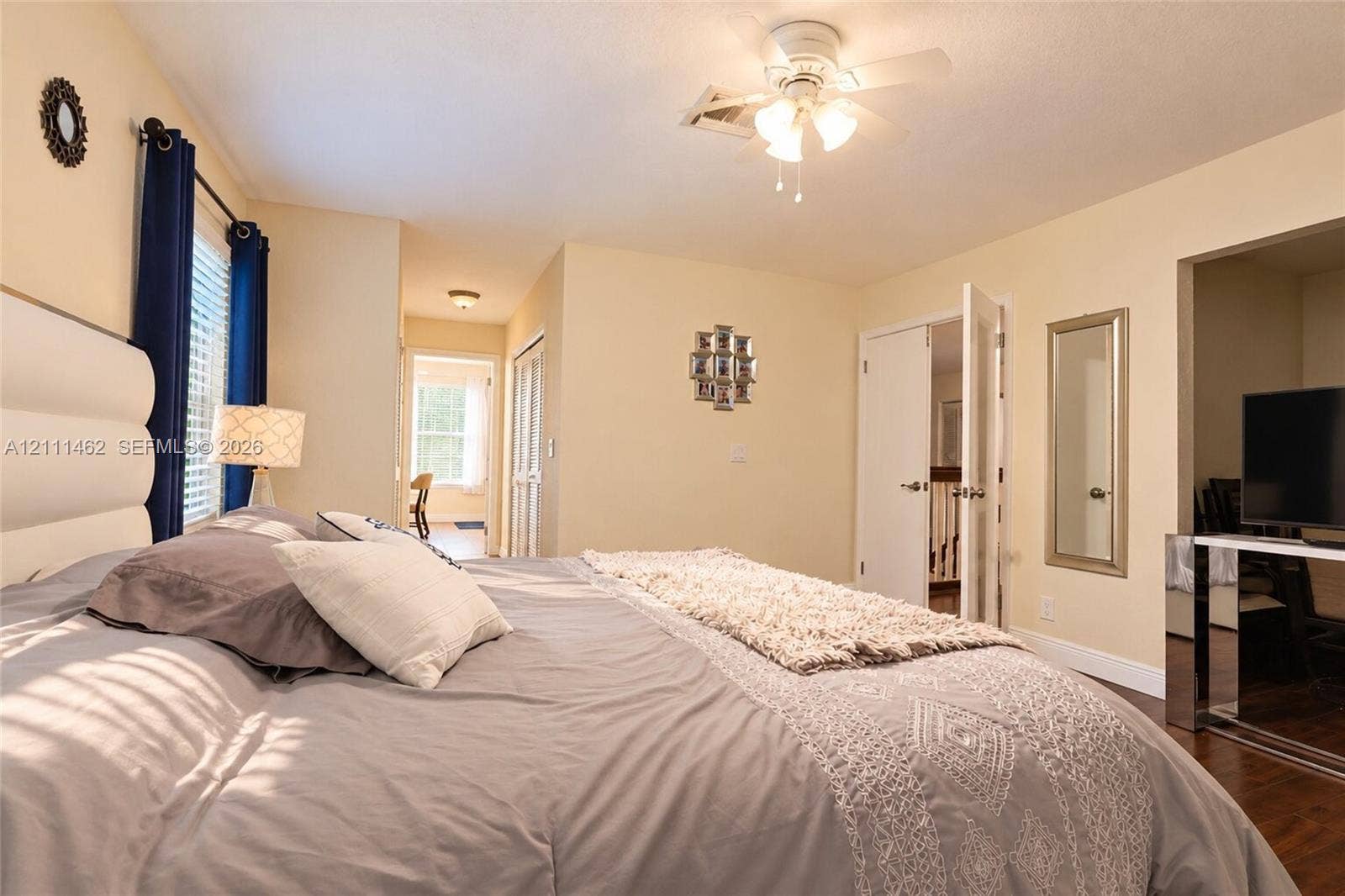 Room featuring wood-finish flooring, a ceiling fan with integrated lighting, and a double-door closet