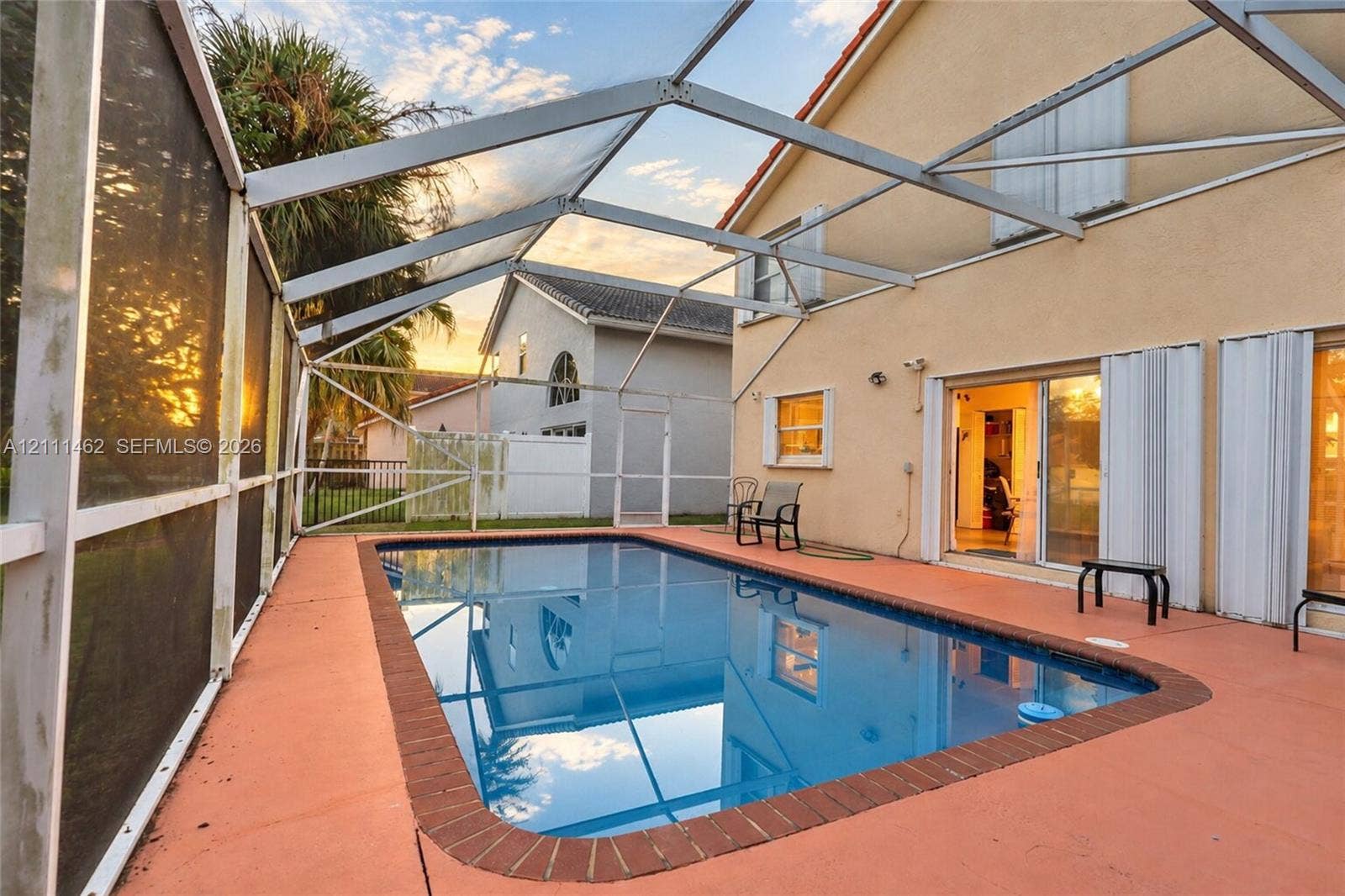 Screened-in patio featuring a rectangular swimming pool with brick coping and a painted concrete deck