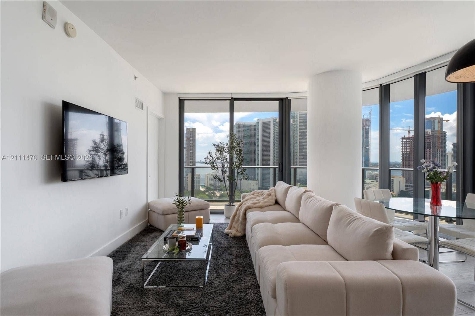 Floor-to-ceiling windows, high-rise urban skyline scenery, and neutral ceramic tile flooring