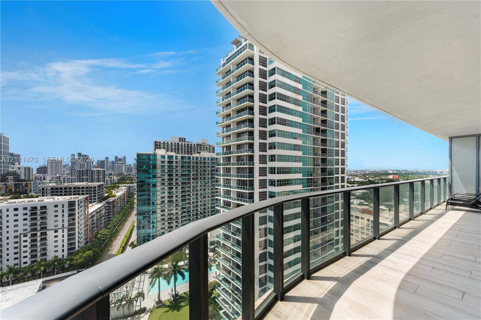 Covered balcony featuring wood-finish tile flooring, glass panel railings, and metal handrails