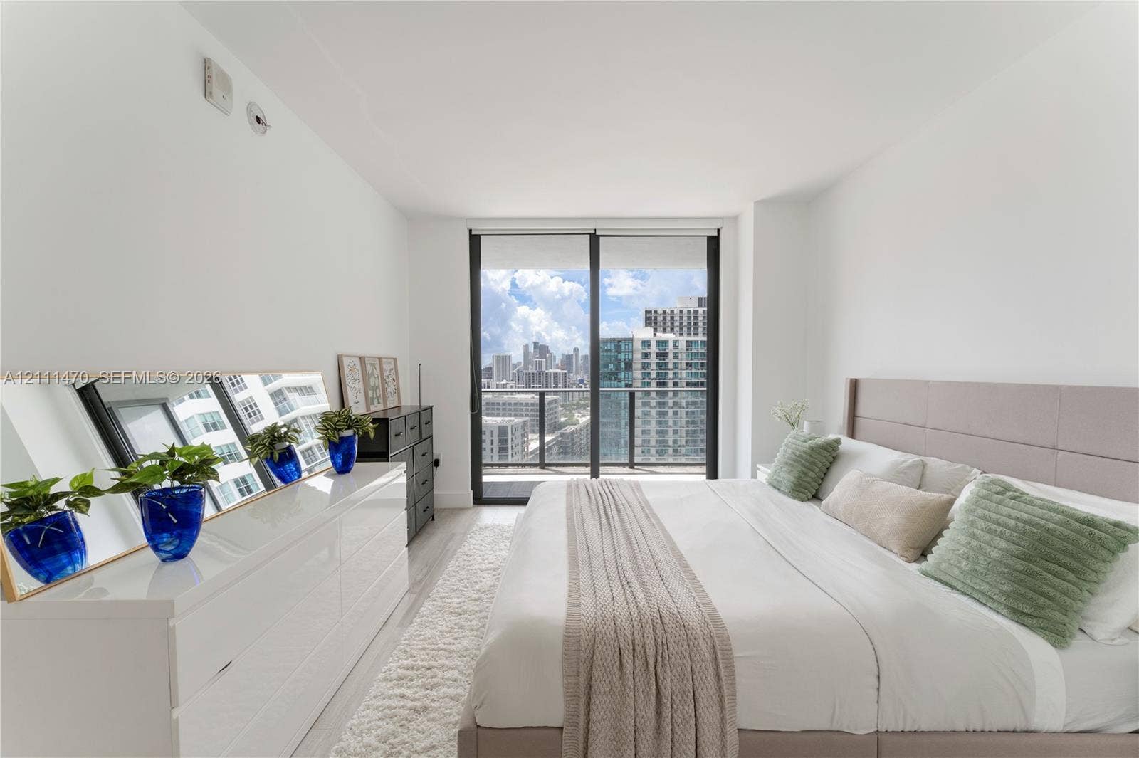 Neutral-toned room featuring floor-to-ceiling sliding glass doors, a balcony with a metal railing, and light-toned flooring
