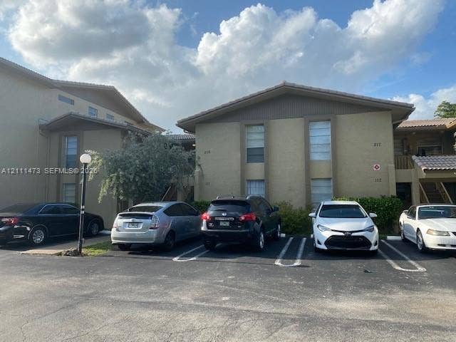 11101 Royal Palm Boulevard, #113, Coral Springs, Coral Springs, FL 33065 Multi-story exterior featuring a textured stucco finish, low-pitched rooflines, and assigned asphalt parking