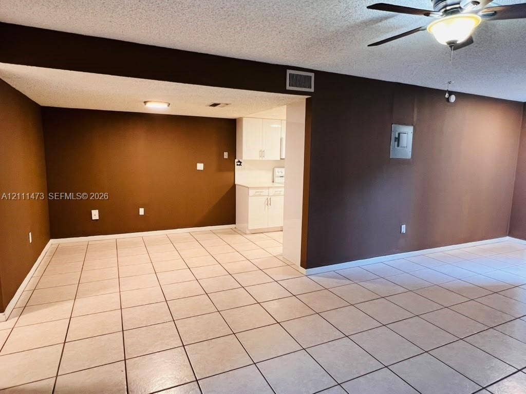 11101 Royal Palm Boulevard, #113, Coral Springs, Coral Springs, FL 33065 Ceramic tile flooring, white cabinetry, ceiling fan with integrated light fixture, and textured ceilings