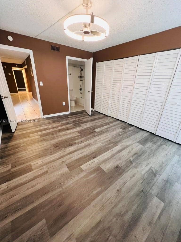 11101 Royal Palm Boulevard, #113, Coral Springs, Coral Springs, FL 33065 Wood-finish flooring, full-wall louvered-door closet, brushed nickel circular chandelier, and direct access to an attached bathroom
