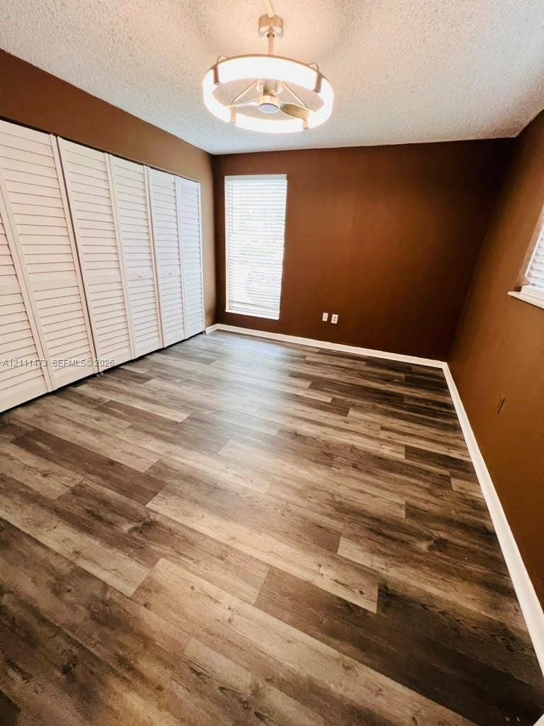 11101 Royal Palm Boulevard, #113, Coral Springs, Coral Springs, FL 33065 Room featuring wood-finish flooring, floor-to-ceiling louvered closet doors, and a contemporary circular flush-mount ceiling fixture with integrated lighting