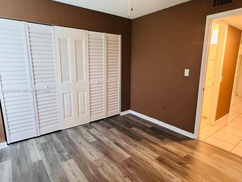 11101 Royal Palm Boulevard, #113, Coral Springs, Coral Springs, FL 33065 Room featuring wood-finish flooring and floor-to-ceiling white louvered-style closet doors