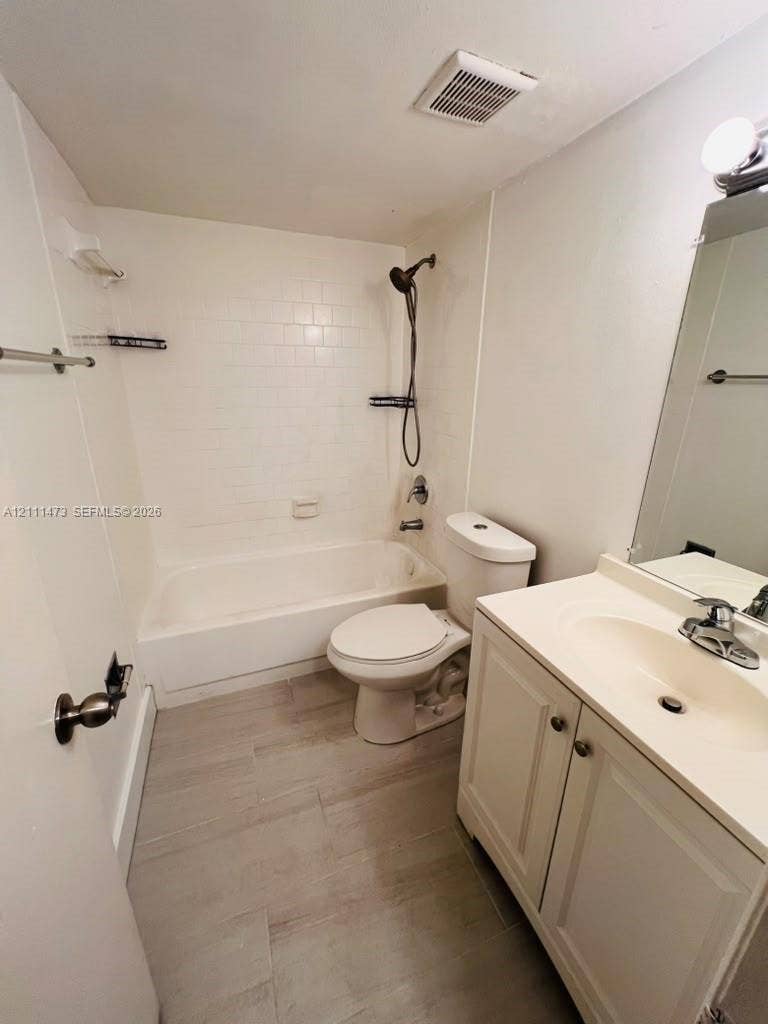 11101 Royal Palm Boulevard, #113, Coral Springs, Coral Springs, FL 33065 Bathroom featuring a tub-shower combination with white subway-style tile, vanity with an integrated basin, wood-finish tile flooring, and a wall-mounted hand-held shower fixture