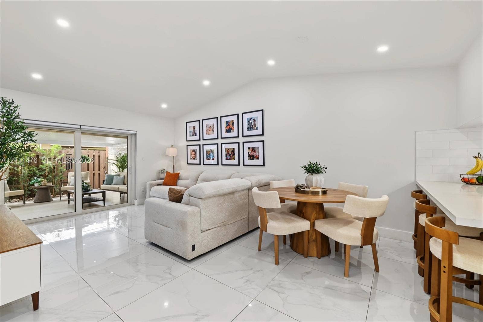 Polished tile flooring, recessed lighting, vaulted ceilings, and sliding glass doors with direct patio access