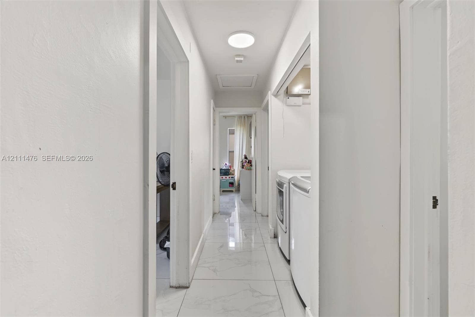 Interior hallway featuring large-format stone-look tile flooring and a flush-mount circular ceiling light