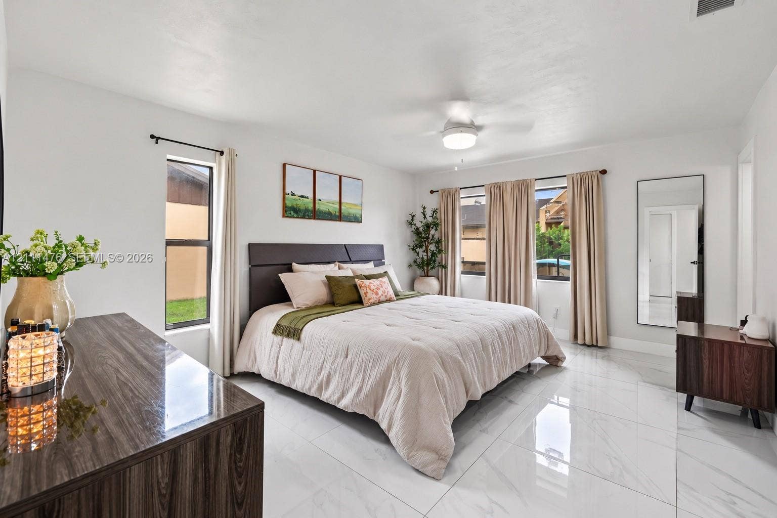 Spacious interior featuring large-format tile flooring with polished finish, ceiling-mounted light fixture with integrated fan, and oversized windows