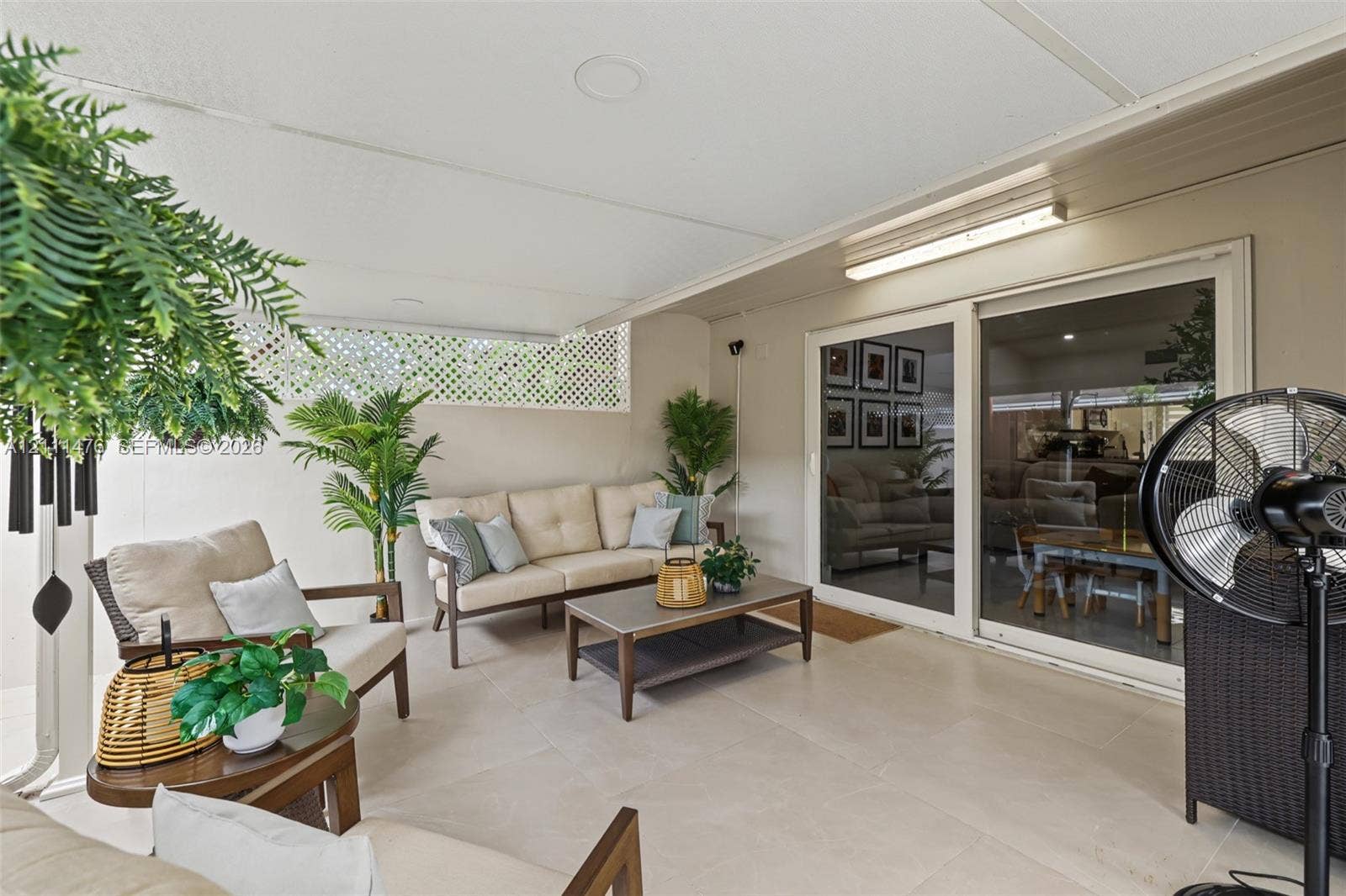 Covered patio featuring neutral tile flooring, lattice wall paneling, and sliding glass door access