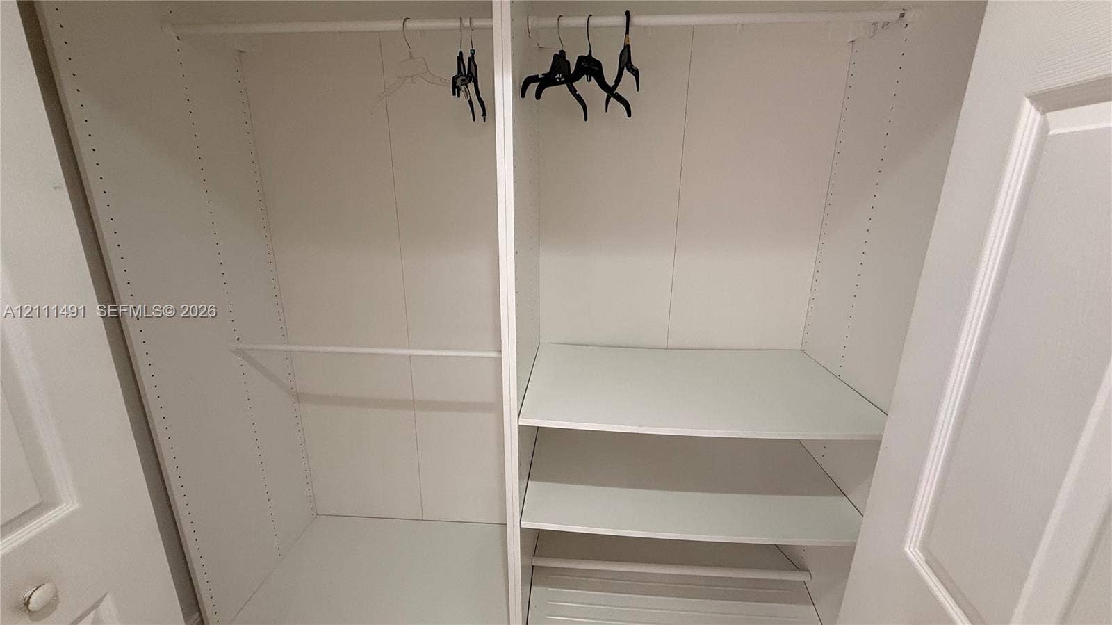 Built-in closet featuring white interior shelving, dual hanging rods, and adjustable shelving tracks