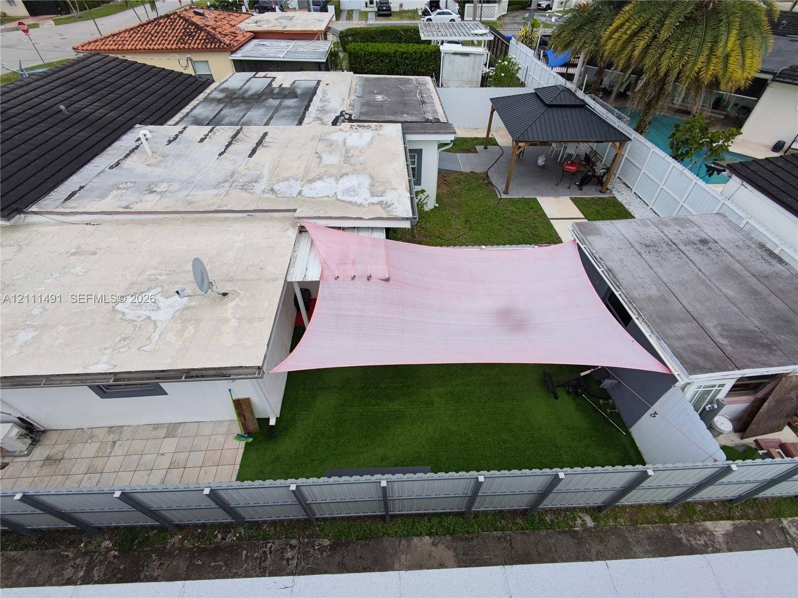 Fenced backyard featuring synthetic turf, a hardscaped patio area, and a permanent gazebo structure