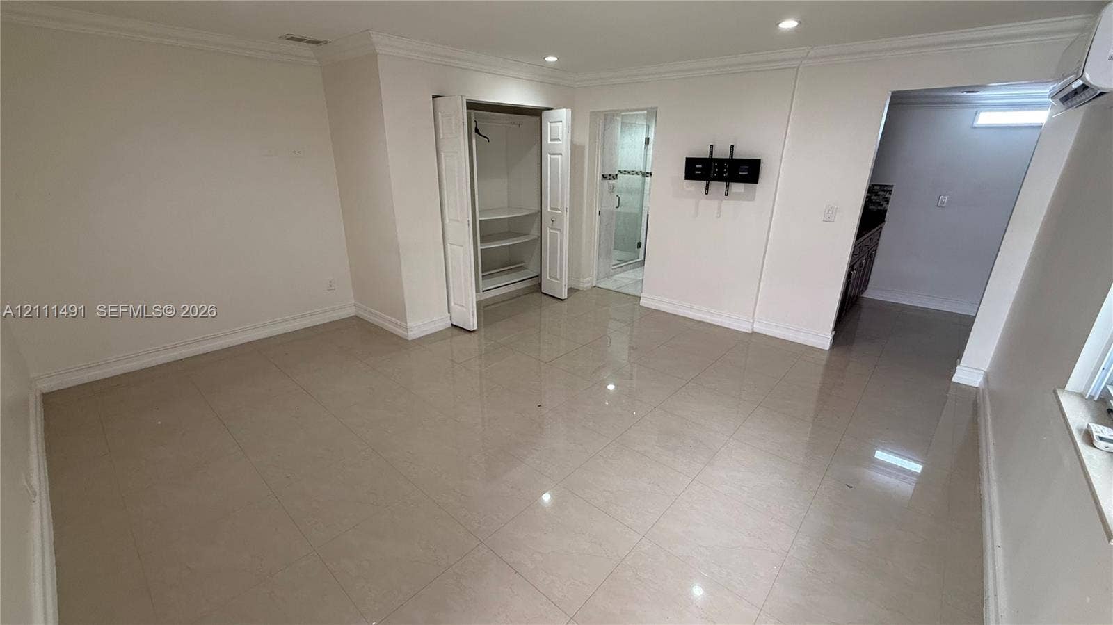 Polished tile flooring, recessed lighting, crown molding, built-in closet shelving, and a wall-mounted glass-enclosed shower