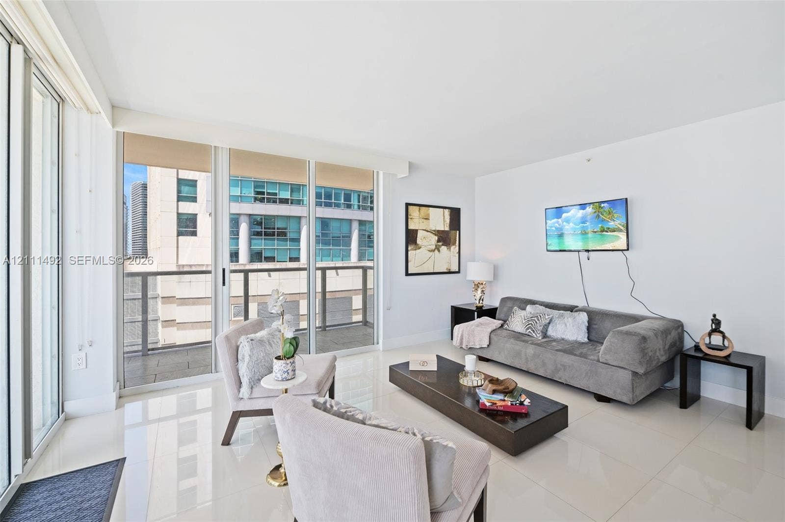 Floor-to-ceiling glass sliding doors, polished tile flooring, and a private balcony featuring metal railing