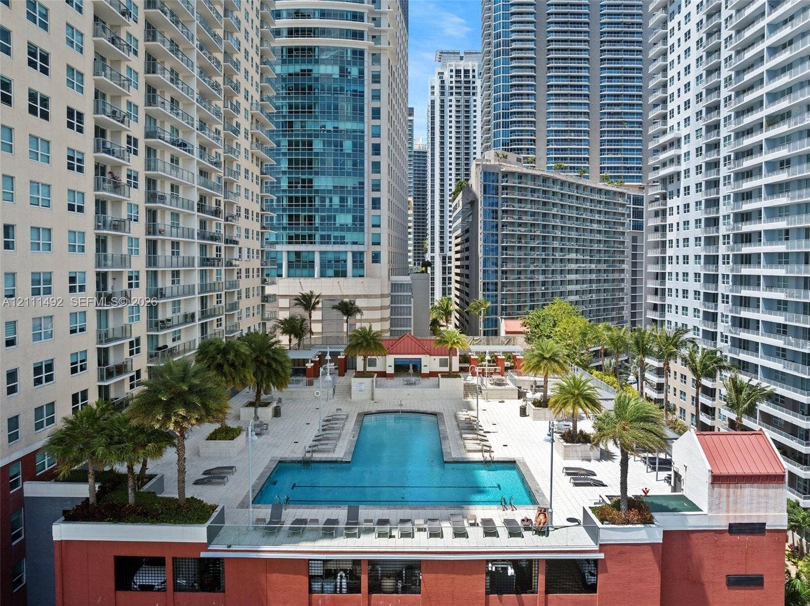 Outdoor swimming pool featuring stone deck surround, integrated palm tree landscaping, built-in structural planters, and masonry architecture