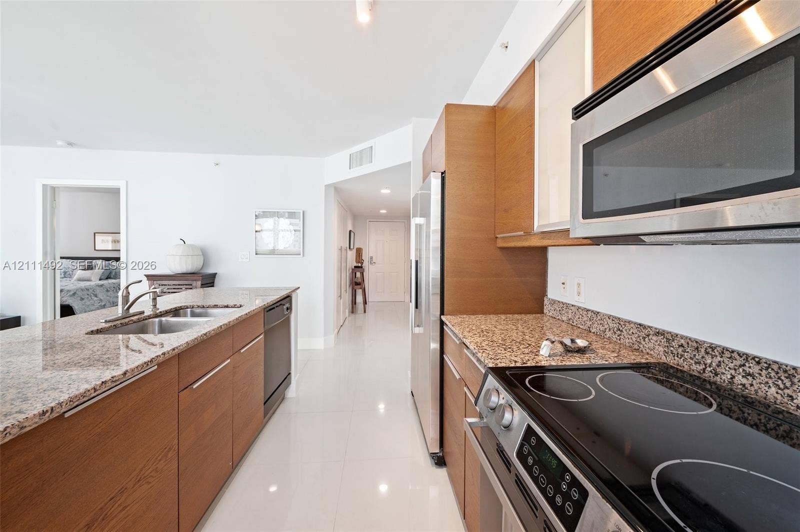 Kitchen featuring wood-finish cabinetry, stone countertops, stainless steel appliances, and tile flooring