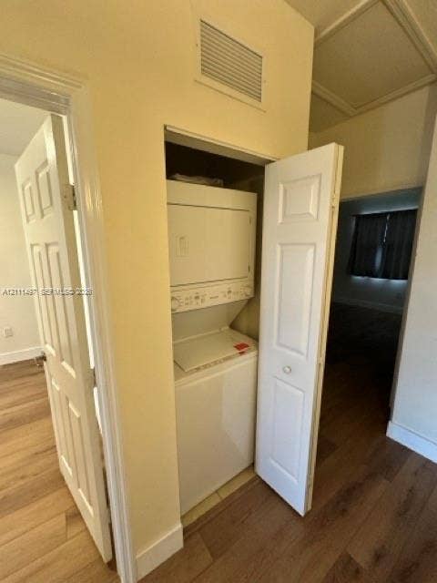 3210 SE 6th Street, Homestead, Homestead, FL 33033 Laundry closet featuring a stackable washer and dryer unit, wood-finish flooring, and panel-style interior doors