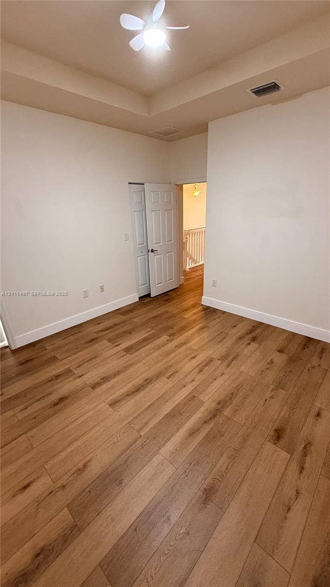 3210 SE 6th Street, Homestead, Homestead, FL 33033 Room featuring wood-finish flooring, tray ceiling, dual-panel interior closet doors, and a ceiling fan with integrated lighting