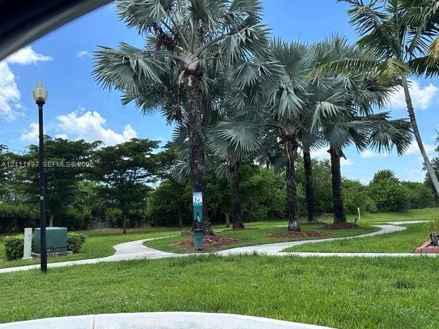 3210 SE 6th Street, Homestead, Homestead, FL 33033 Expansive lawn featuring established palm trees, a concrete pathway, and decorative street lighting