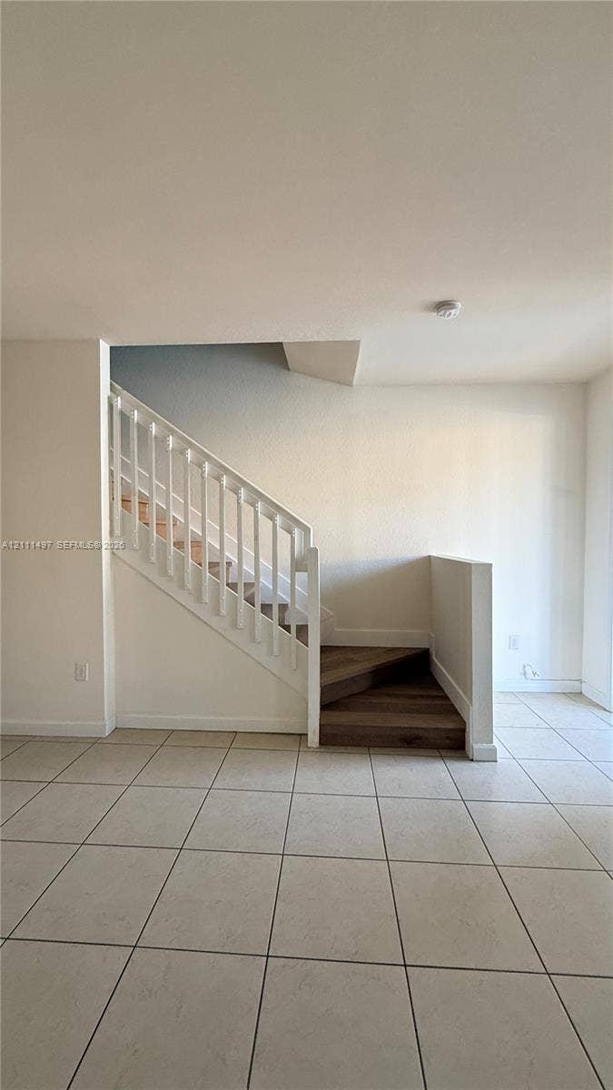 3210 SE 6th Street, Homestead, Homestead, FL 33033 Staircase featuring white balusters, wood-finish treads, and neutral tile flooring