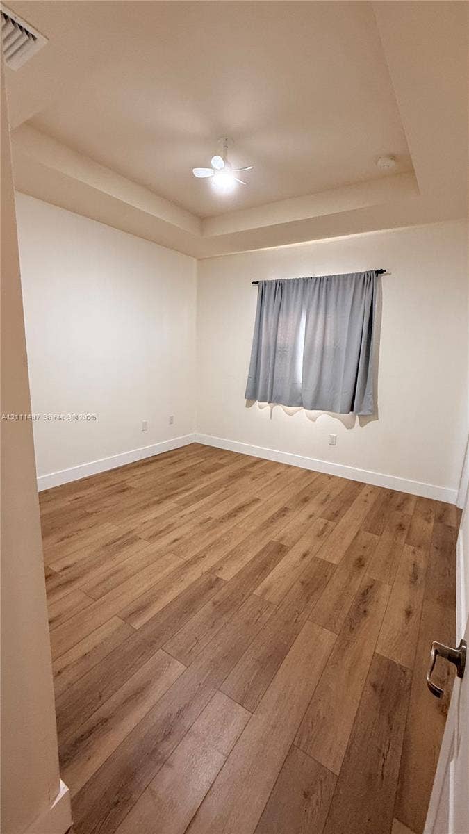 3210 SE 6th Street, Homestead, Homestead, FL 33033 Tray ceiling featuring a recessed center, wood-finish flooring, and a central ceiling fan with an integrated light fixture