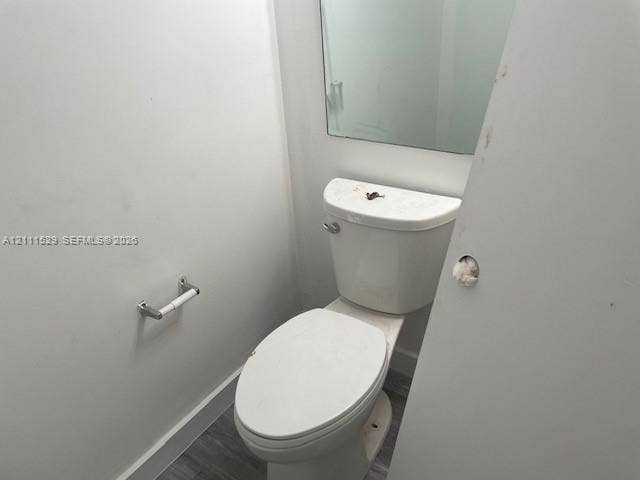 406 NW 68th Avenue, #118, Plantation, Plantation, FL 33317 Restroom featuring a wall-mounted mirror, white elongated toilet, and wood-finish flooring