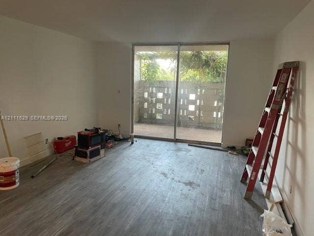 406 NW 68th Avenue, #118, Plantation, Plantation, FL 33317 Interior space featuring wood-finish flooring, floor-to-ceiling sliding glass doors, and a private patio enclosed by decorative concrete block screening