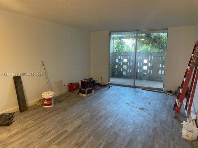 406 NW 68th Avenue, #118, Plantation, Plantation, FL 33317 Interior space featuring wood-finish flooring and expansive metal-framed sliding glass doors opening to a concrete masonry unit privacy wall