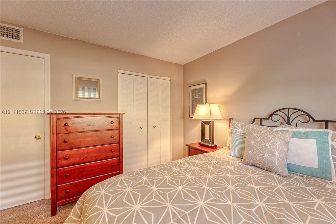 Neutral wall tones, dual-panel closet doors, and textured carpeting