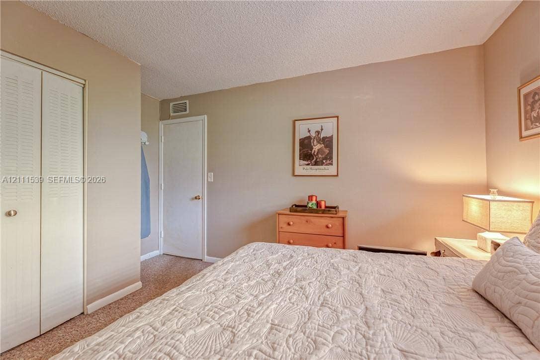 Room featuring neutral-toned walls, carpeted flooring, and white louvered-panel closet doors