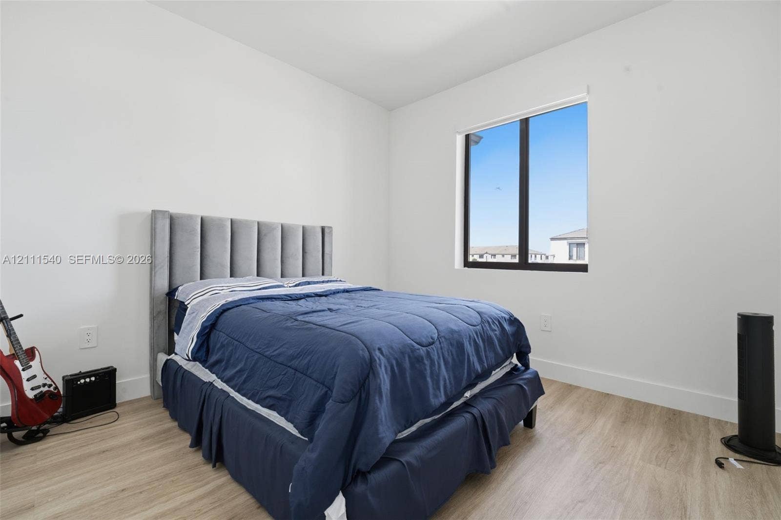 Neutral wall finish, wood-finish flooring, and a large window with black frame
