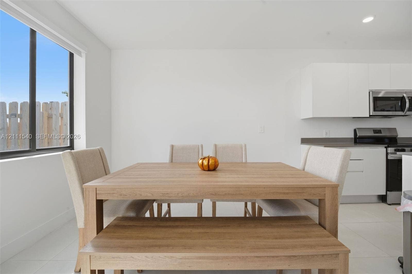 Kitchen featuring white flat-panel cabinetry, stainless steel appliances, and large-format tile flooring, complemented by a floor-to-ceiling window