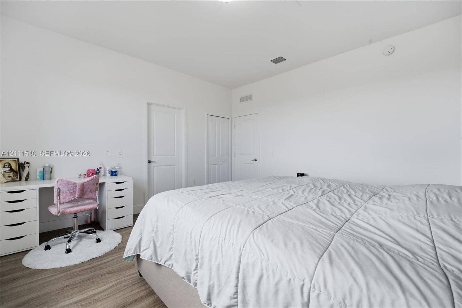Neutral-toned interior featuring wood-finish flooring, crisp white walls, and multiple solid-core panel doors