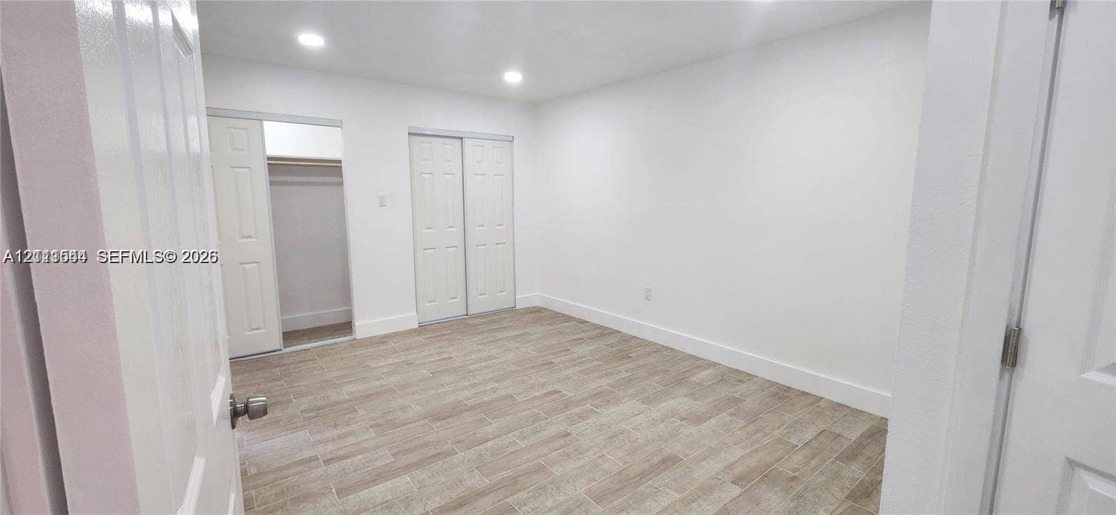 19771 SW 114th Avenue, #227, Miami, Miami, FL 33157 Neutral interior space featuring wood-finish tile flooring, recessed lighting, and dual reach-in closets with six-panel doors