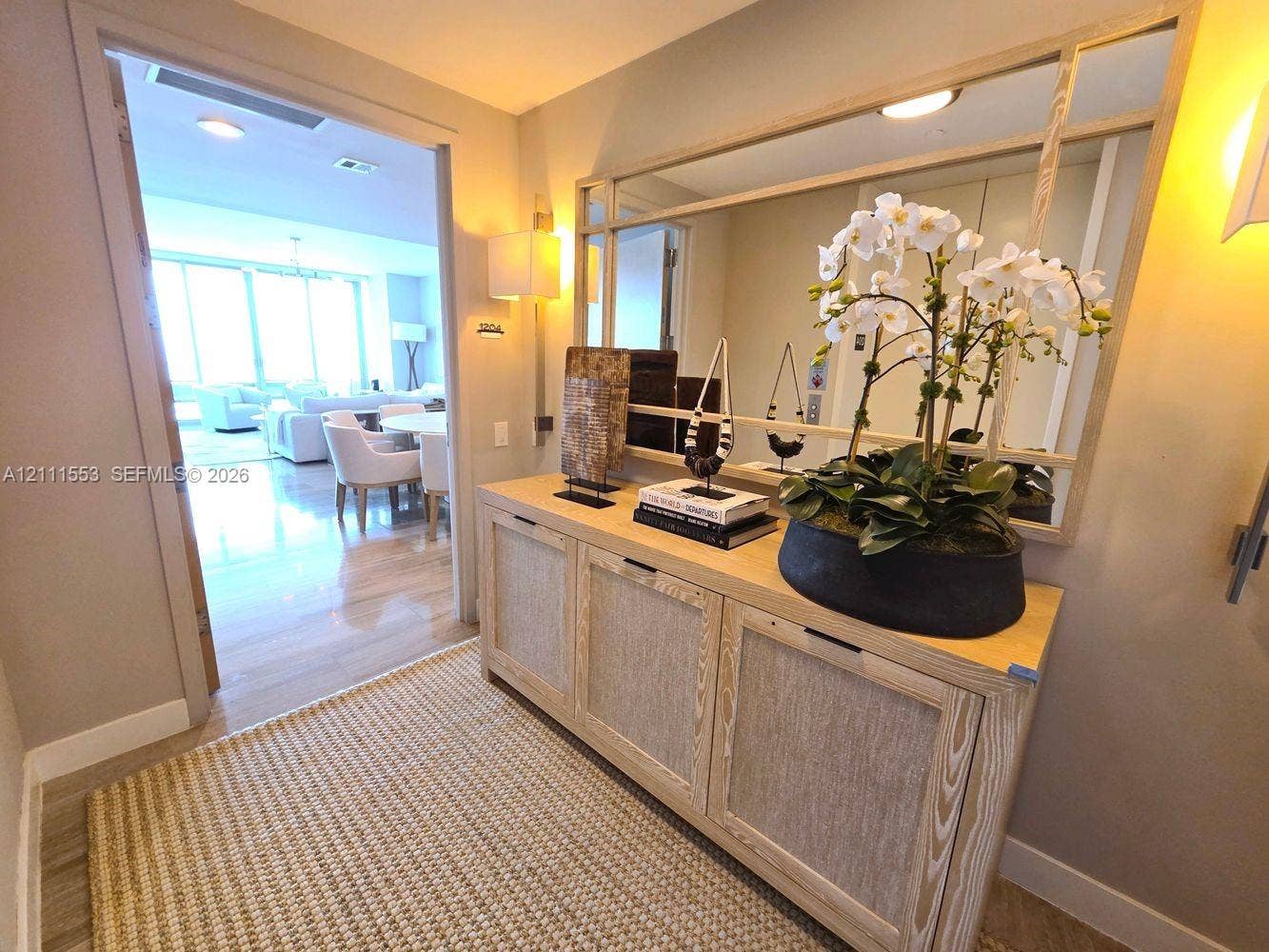 Entryway featuring a large rectangular mirror with wood-tone frame, light wood built-in cabinetry, and wall-mounted sconce lighting