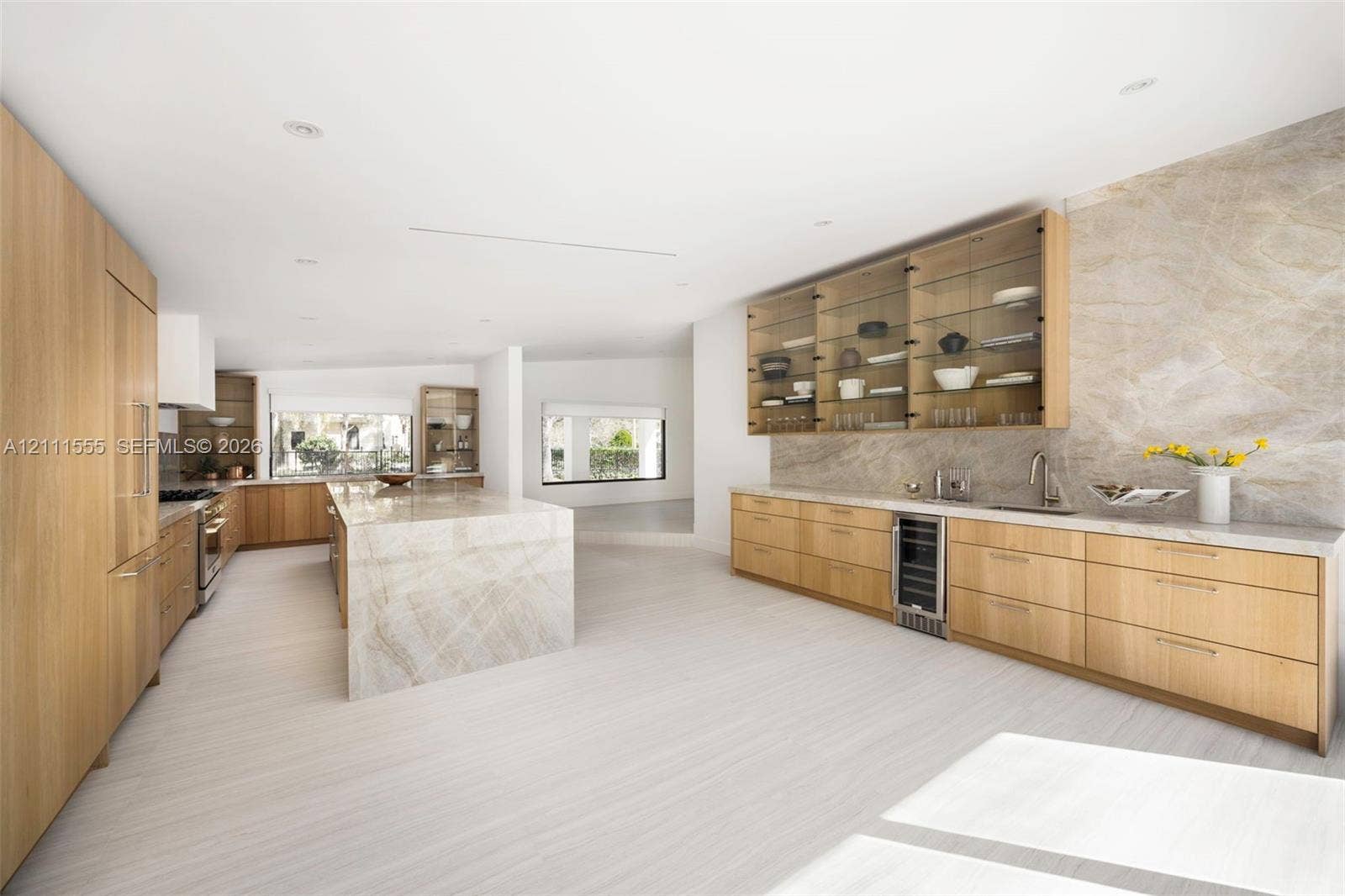 8800 SW 118th Street, Miami, Miami, FL 33176 Custom wood-finish cabinetry, expansive stone-clad island, full-height stone backsplash, glass-front upper storage, and integrated beverage cooler
