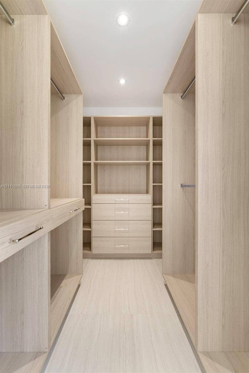 8800 SW 118th Street, Miami, Miami, FL 33176 Custom closet organization system featuring light wood-finish cabinetry, built-in shelving, integrated drawers with metallic hardware, and recessed lighting