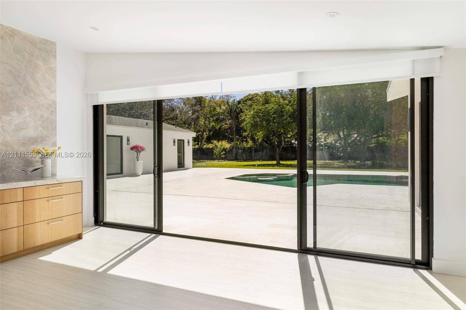 8800 SW 118th Street, Miami, Miami, FL 33176 Floor-to-ceiling sliding glass doors, built-in natural wood cabinetry with stone countertop, large format light-toned tile flooring, concrete patio, and in-ground pool