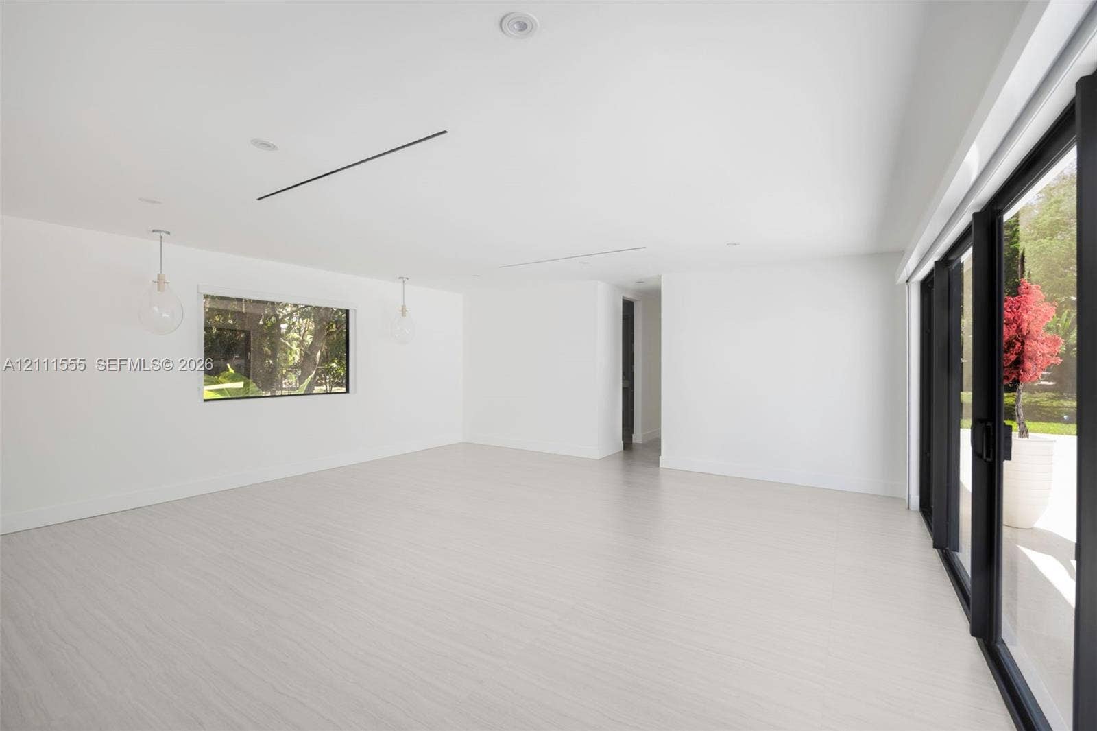 8800 SW 118th Street, Miami, Miami, FL 33176 Open-concept interior with light-toned wood-finish flooring, recessed lighting, glass pendant fixtures, and floor-to-ceiling black-framed sliding glass doors